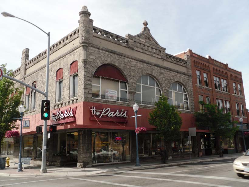 The exterior of "The Paris" restaurant in Pocatello, Idaho, featuring stone architecture, red awnings, and streetlights on a sunny day.